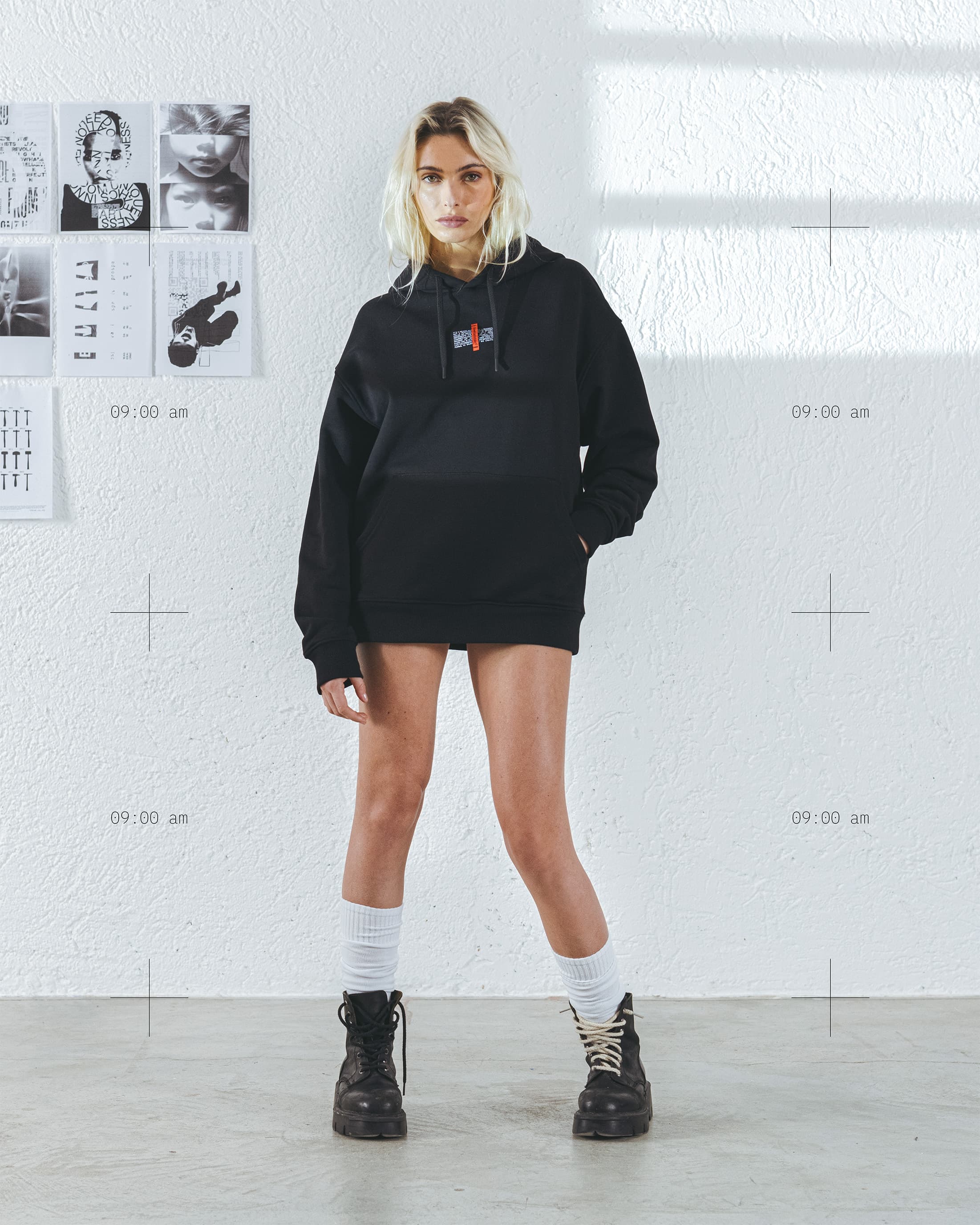 Modella in felpa nera oversize davanti al muro bianco